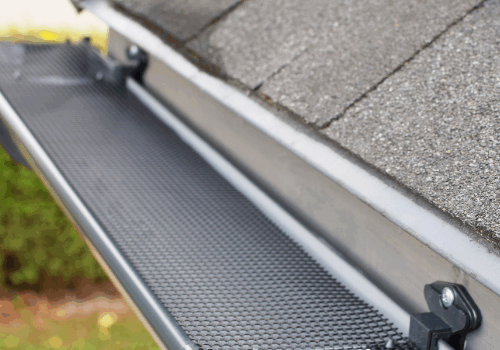 Close-up of a gutter system with a newly installed gutter cover to prevent debris buildup.